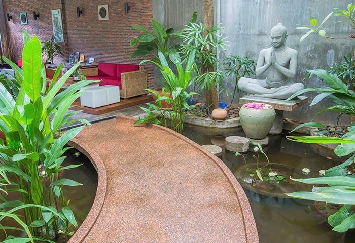 Casa Villa Independence: Gay-friendly hotel interior. Bridge over water feature with Buddha statue. Relaxation area with red sofa.
