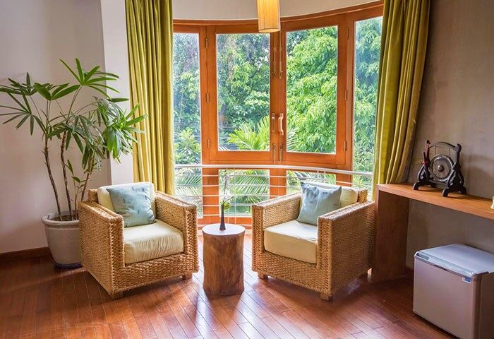 Casa Villa Independence: Gay-friendly hotel room with two wicker chairs, a small table, and a large window with a view of lush greenery.