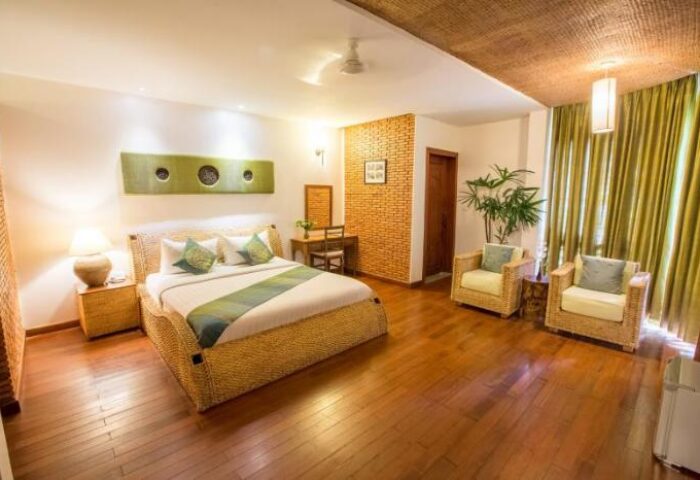 Casa Villa Independence gay-friendly hotel room. Wicker bed frame, chairs, and ceiling detail. Hardwood floors, desk, and green accents.