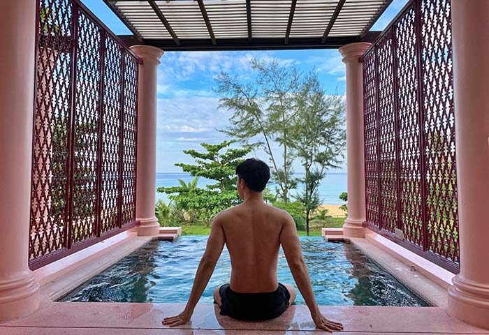 Gay man at Centara Grand Beach Resort Phuket pool with ocean view. Gay-friendly hotel for LGBT travel in Phuket, Thailand.