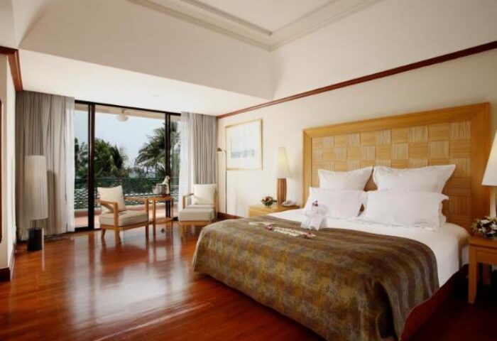 Centara Grand Beach Resort Samui gay-friendly hotel room. Luxurious bedroom with balcony, chairs, and sea view. Perfect for gay travelers.