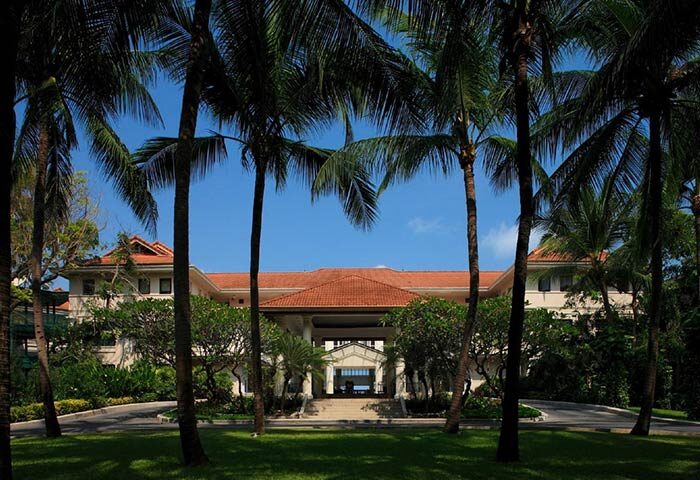 Centara Grand Beach Resort Samui view through palm trees. Gay-friendly hotel in Thailand with tropical landscape. Beachfront resort.