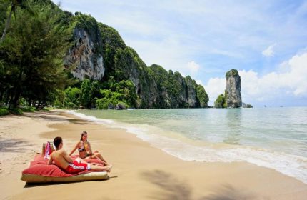 Couple relaxing on beach at gay-friendly Centara Grand Beach Resort & Villas Krabi. Tropical paradise, clear water, idyllic vacation.