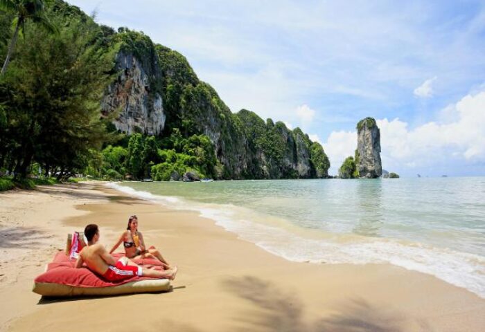 Couple relaxing on beach at gay-friendly Centara Grand Beach Resort & Villas Krabi. Tropical paradise, clear water, idyllic vacation.