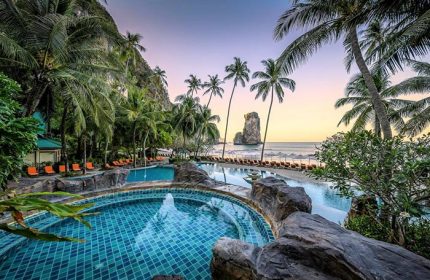 Centara Grand Beach Resort & Villas Krabi pool view. Gay-friendly hotel with beach access, palm trees, and ocean views at sunset.