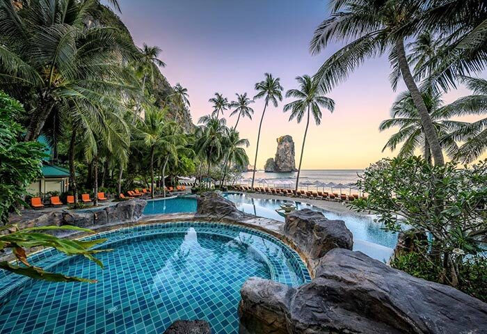Centara Grand Beach Resort & Villas Krabi pool view. Gay-friendly hotel with beach access, palm trees, and ocean views at sunset.