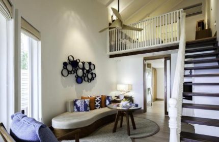 Centara Grand Island Resort & Spa, Maldives suite. Lofted space with stairs, seating, and modern decor. Gay-friendly hotel for men's travel.