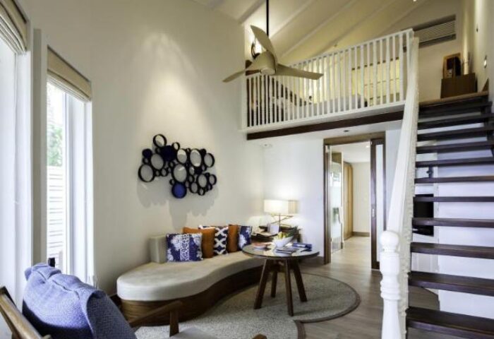 Centara Grand Island Resort & Spa, Maldives suite. Lofted space with stairs, seating, and modern decor. Gay-friendly hotel for men's travel.