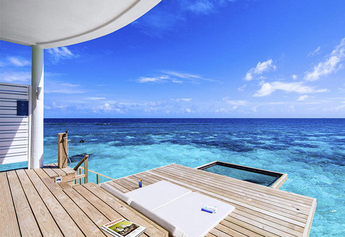 Centara Grand Island Resort & Spa Maldives gay-friendly hotel. Overwater bungalow deck with ocean view, lounge chair, & swim platform.