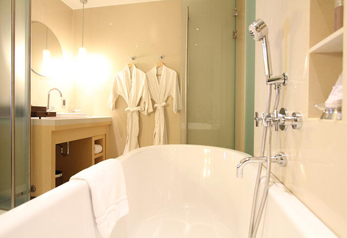 Centara Grand at Central World Hotel bathroom. Bathtub, shower, sink, and robes. SHA Certified gay-friendly hotel in Bangkok, Thailand.