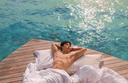 Gay-friendly Centara Ras Fushi Resort & Spa Maldives: Man relaxing on a deck over turquoise water. Ideal gay travel destination.