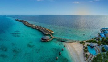 Centara Ras Fushi Resort & Spa Maldives aerial view. Gay-friendly hotel with overwater bungalows, pool, beach, and turquoise water.