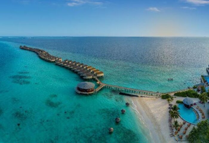 Centara Ras Fushi Resort & Spa Maldives aerial view. Gay-friendly hotel with overwater bungalows, pool, beach, and turquoise water.