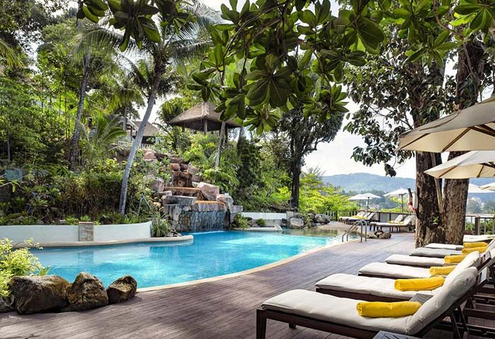 Pool view at Gay-Friendly Centara Villas Phuket Hotel. Loungers, umbrellas, and lush greenery create a relaxing gay travel getaway.