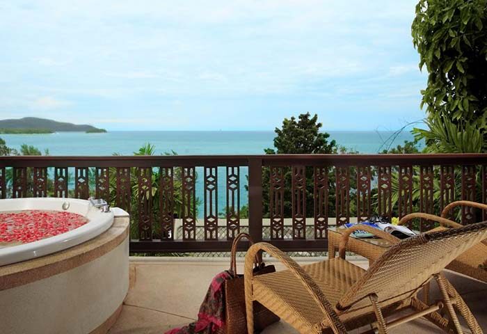 Gay-Friendly Centara Villas Phuket Hotel balcony view. Hot tub with flower petals, lounge chairs, & ocean vista. Perfect for gay travel in Phuket.