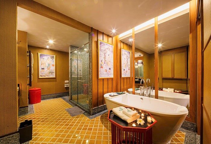 Chala Number 6 gay-friendly hotel bathroom with tub, shower, yellow tiled floor, and artwork. A luxurious space for gay travelers.