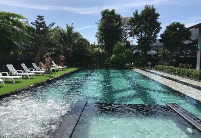 ChaoKoh Phi Phi Hotel & Resort pool view. Gay-friendly hotel with sunbeds, lush greenery, and clear turquoise water. Ideal for gay travel.