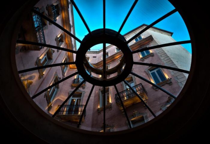 Chateau Monfort Hotel view through a round window. Gay-friendly hotel with balconies. Milan, Italy. Upscale travel for gay men.