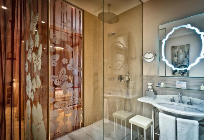 Chateau Monfort Hotel's bathroom. Shower with butterfly design, illuminated mirror, and marble sink. Gay-friendly hotel for gay men travel.