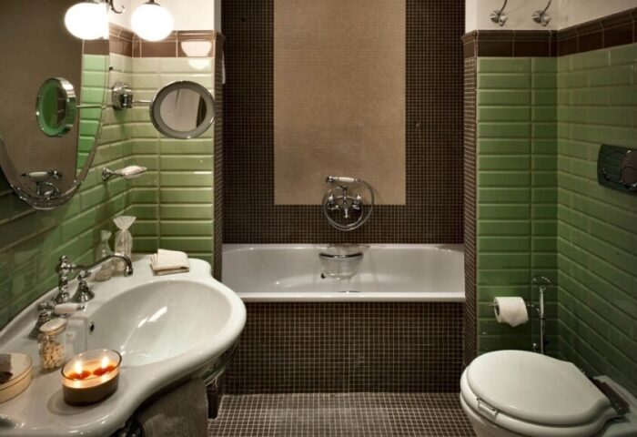 Bathroom at gay-friendly Chateau Monfort Hotel. Green and brown tiles, bathtub, sink, and toilet. Elegant design for gay men travelers.