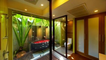 Chaweng Regent Beach Resort's gay-friendly hotel bathroom with tub filled with rose petals, plants, and modern design. Luxurious gay travel.