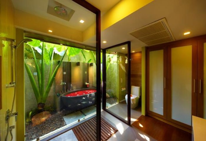 Chaweng Regent Beach Resort's gay-friendly hotel bathroom with tub filled with rose petals, plants, and modern design. Luxurious gay travel.