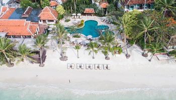 Aerial view of Chaweng Regent Beach Resort, a gay-friendly hotel. Palm trees, pool, beach loungers, and traditional Thai architecture.