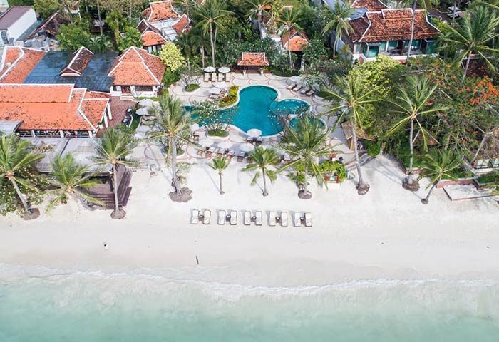 Aerial view of Chaweng Regent Beach Resort, a gay-friendly hotel. Palm trees, pool, beach loungers, and traditional Thai architecture.