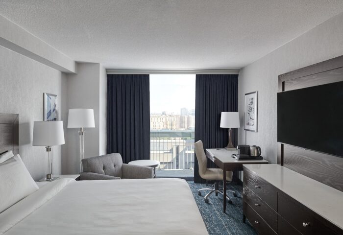 Chelsea Hotel Toronto guest room. Gay-friendly hotel featuring a bed, desk, TV, and balcony with city view. Modern decor.