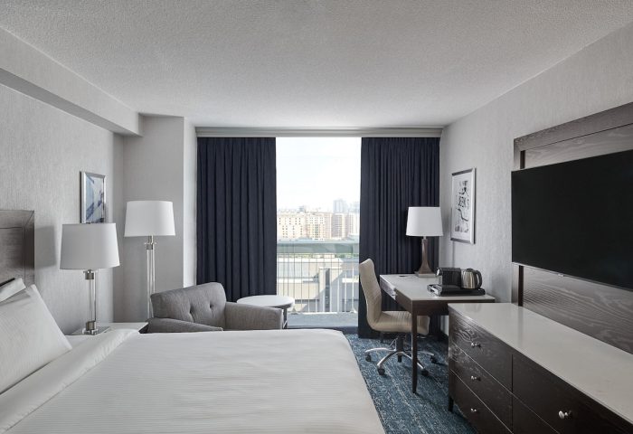 Chelsea Hotel Toronto guest room. Gay-friendly hotel featuring a bed, desk, TV, and balcony with city view. Modern decor.