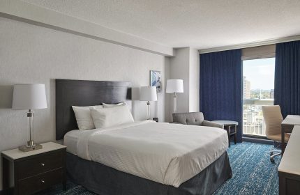 Chelsea Hotel Toronto room. Gay-friendly hotel with a bed, desk, chair, and city view. A comfortable stay for gay travelers.