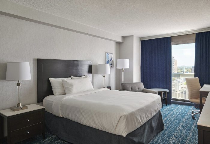 Chelsea Hotel Toronto room. Gay-friendly hotel with a bed, desk, chair, and city view. A comfortable stay for gay travelers.
