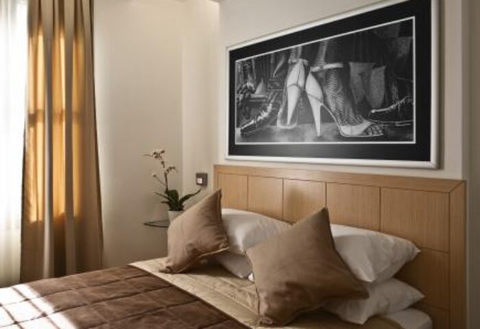 Gay-friendly Chic Hotel bedroom with a bed, pillows, and a black and white picture of high heels above the headboard. Stylish decor.