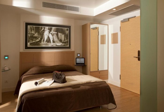 Chic Hotel room interior. Gay-friendly hotel with a brown bed, laptop, and modern decor. Stylish travel for gay men.