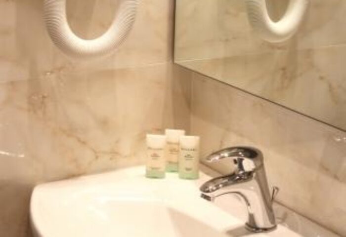 Chic Hotel bathroom sink with toiletries, faucet, mirror, and hair dryer. Gay-friendly hotel with modern amenities for gay men travel.