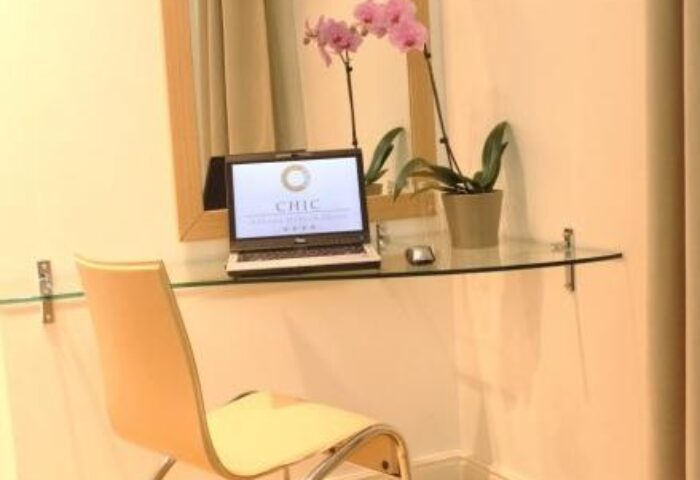 Chic Hotel room desk with laptop and orchid. Gay-friendly hotel offers comfortable workspace for travelers. Interior design for gay men's travel.