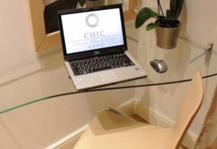 Laptop on glass desk in a Chic Hotel room. Gay-friendly hotel offers modern amenities for travelers. Comfortable workspace for guests.