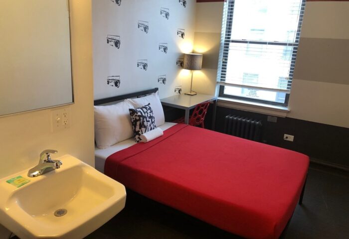 Room at Chicago Getaway Hostel, a gay-friendly hotel. Single bed, desk, sink, and boombox wallpaper. Ideal for gay men's travel in Chicago.