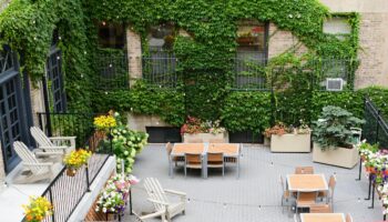 Chicago Getaway Hostel's gay-friendly hotel courtyard. Outdoor seating, tables, and ivy-covered walls create a welcoming space.