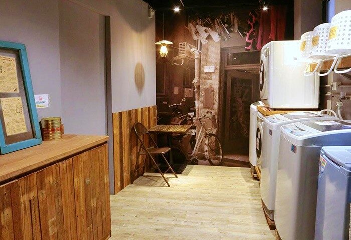 Cho Hotel's laundry room. Gay-friendly hotel with washing machines, a table, and a vintage street scene mural. Unique design for gay travelers.