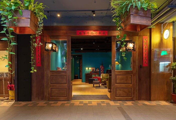 Entrance to Cho Hotel, a gay-friendly hotel. Wooden doors, plants, and Asian-inspired decor create a welcoming atmosphere. Gay travel lodging.