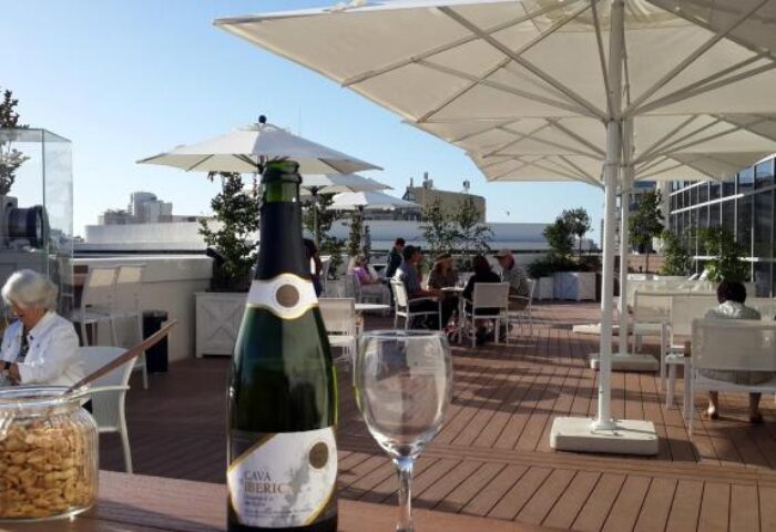 Cinema Hotel's rooftop terrace, an Atlas Boutique Hotel. People enjoy drinks under white umbrellas. Gay-friendly hotel for gay men travel.