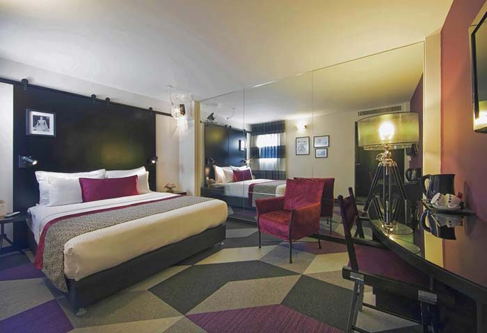Cinema Hotel, an Atlas Boutique Hotel room. Gay-friendly hotel with bed, chair, desk, and geometric carpet. Modern design.