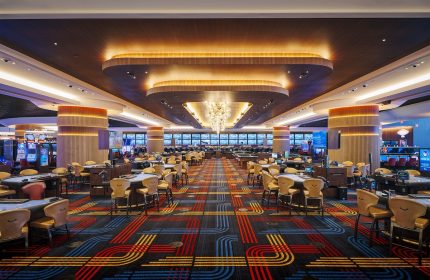 Circa Resort and Casino's gaming floor, an adults-only, gay-friendly hotel. Tables and slot machines under a decorative ceiling.