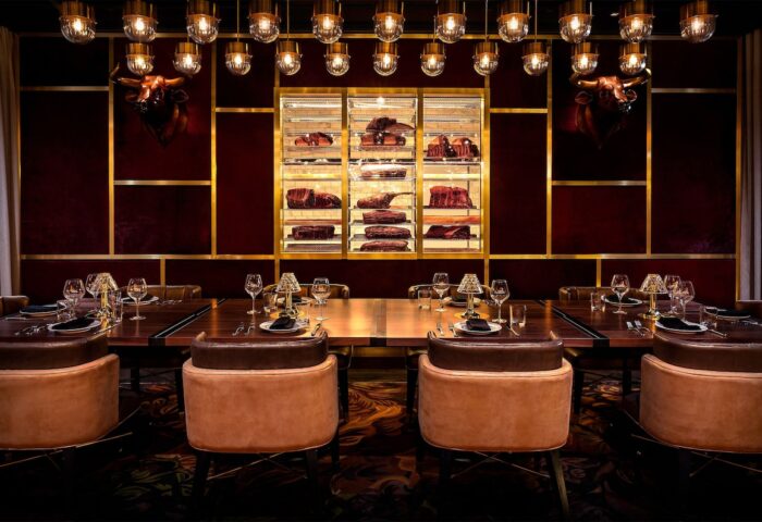 Adults Only Circa Resort and Casino's gay-friendly steakhouse. Long table set for dining, meat display case, bull heads, and stylish lighting.