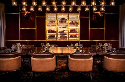 Adults Only Circa Resort and Casino's gay-friendly steakhouse. Long table set for dining, meat display case, bull heads, and stylish lighting.