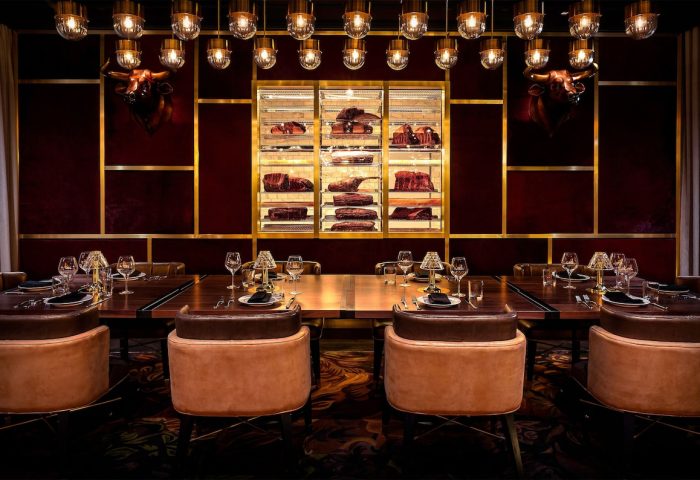 Adults Only Circa Resort and Casino's gay-friendly steakhouse. Long table set for dining, meat display case, bull heads, and stylish lighting.