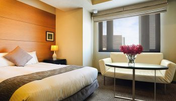 Citadines Central Shinjuku Tokyo gay-friendly hotel room. Bed, sofa, & city view. A comfortable stay in Shinjuku's heart for gay travelers.