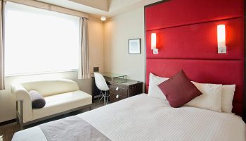 Citadines Central Shinjuku Tokyo room. Gay-friendly hotel with bed, sofa, desk, and red headboard. Ideal for gay travelers in Shinjuku, Tokyo.