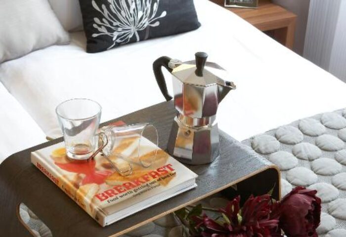 Citadines Holborn-Convent Garden London hotel room detail. Breakfast tray with coffee pot, book, glass, and flowers. Gay-friendly hotel.